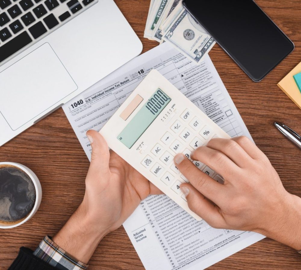 cropped-view-of-man-using-calculator-with-tax-form-and-laptop-on-background-e1670796449877.jpg